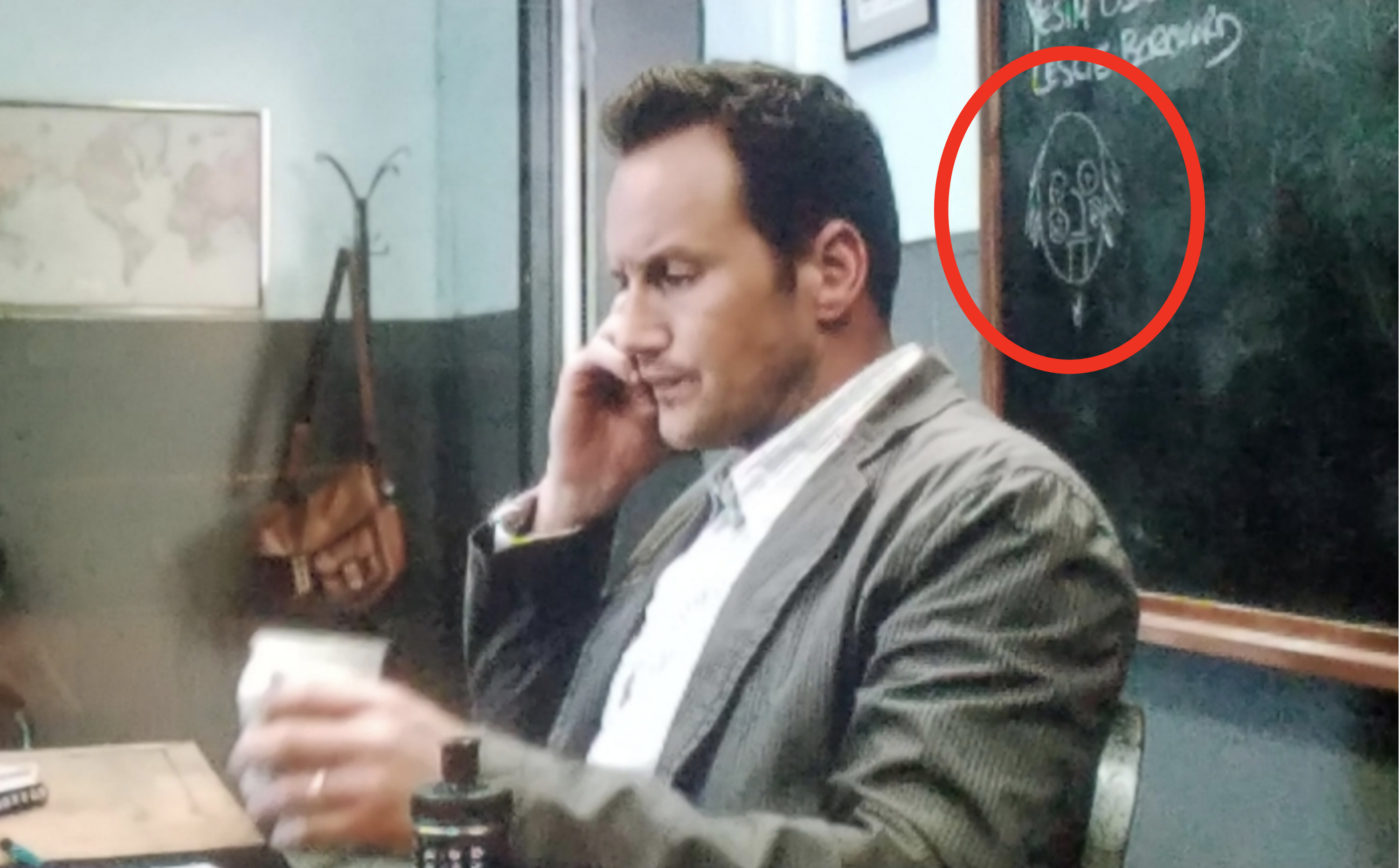 男人在他的桌子上电话和他身后的画圆圈
