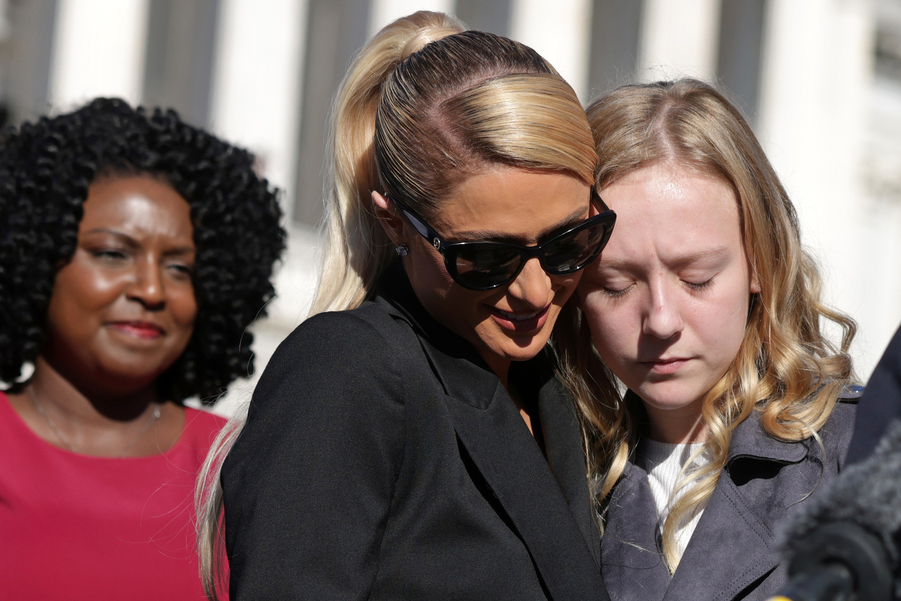 Paris leans in to a young woman while speaking about their experiences in Washington D.C.