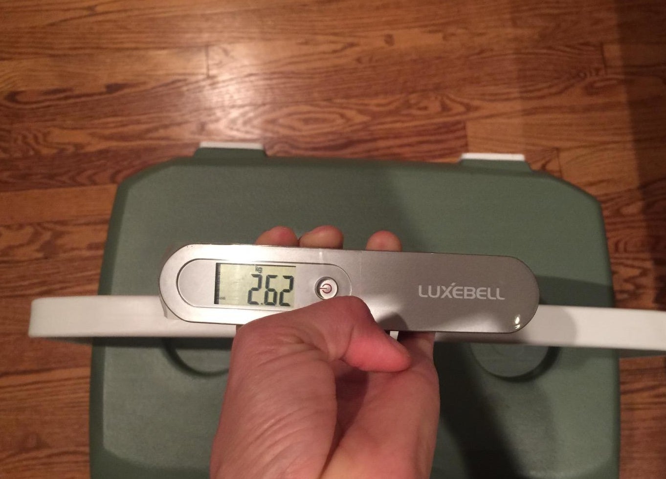 a reviewer using the scale to weigh a suitcase