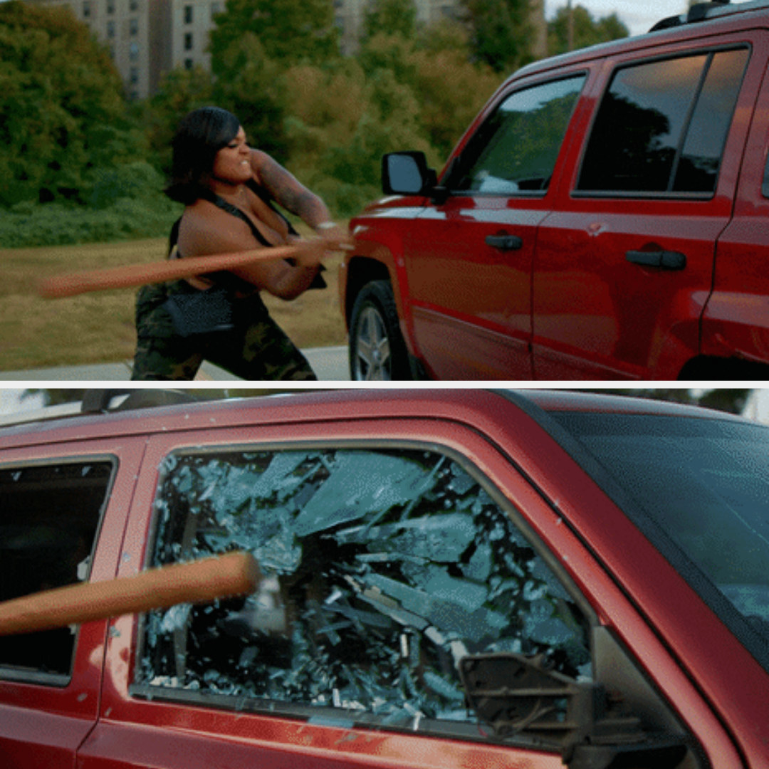 A woman smashing in a car window with a baseball bat