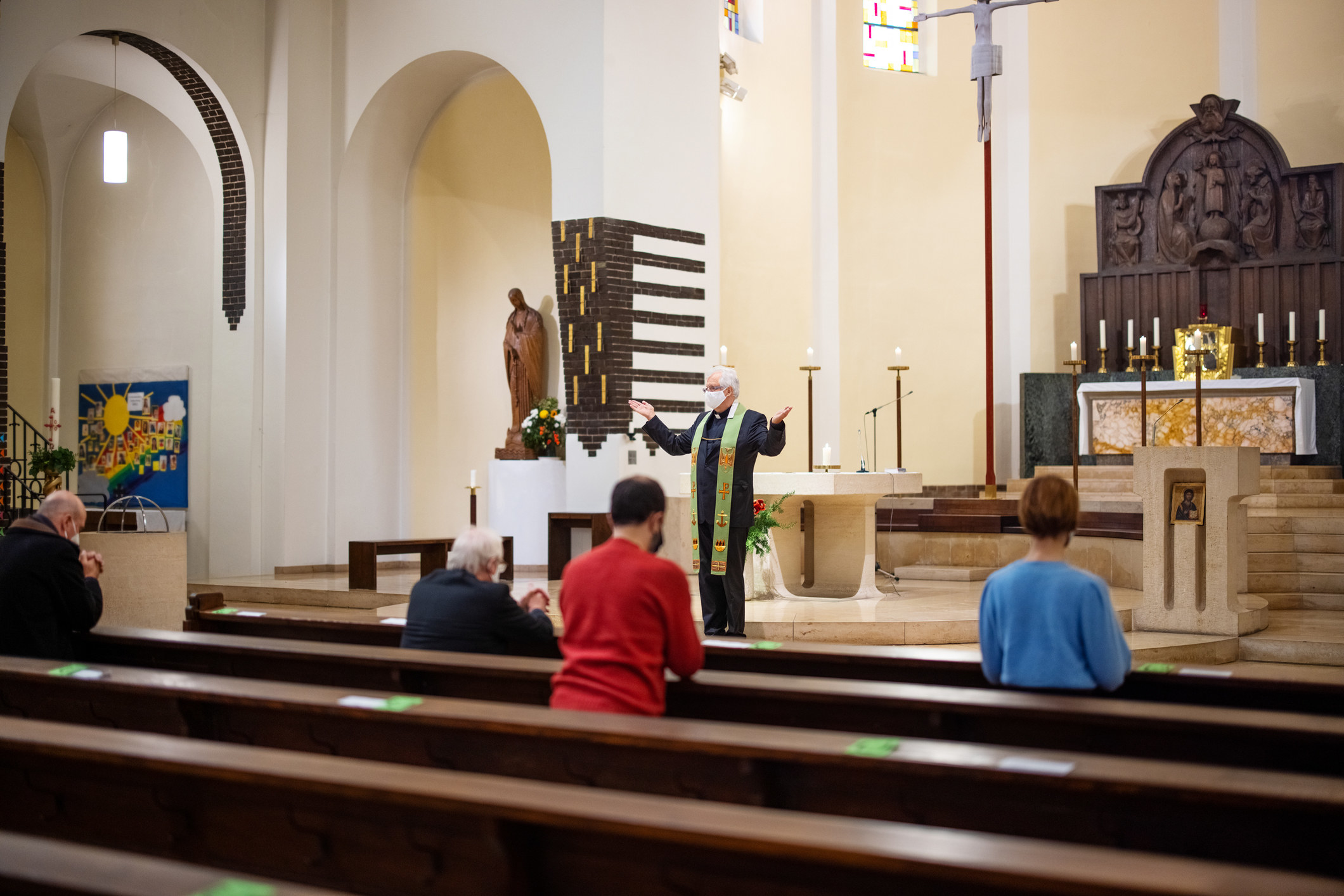 Several people in a church pew listening to a clergyperson