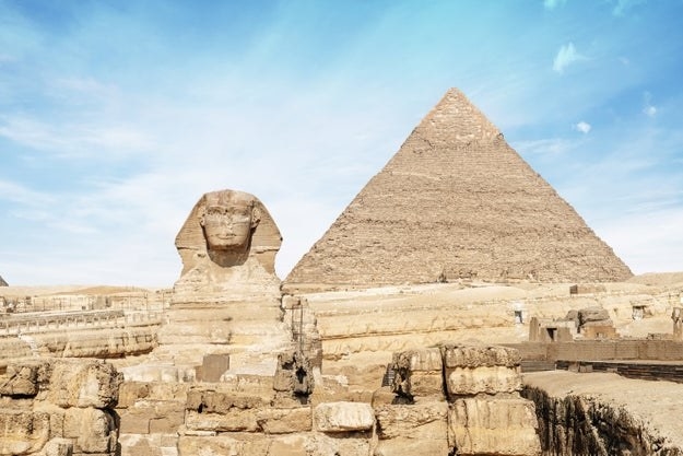 photo of a sphinx statue with a pyramid in the background