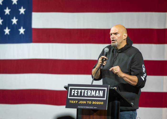 John Fetterman speaking at a podium in front of an American flag