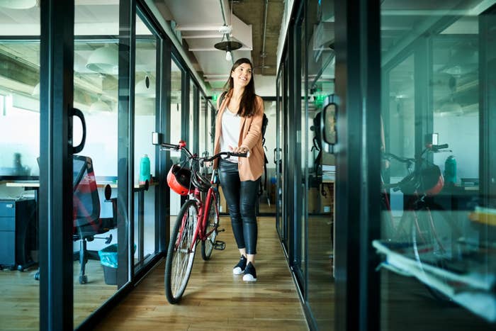 young woman rolling her bike out of the office at five o&#x27;clock