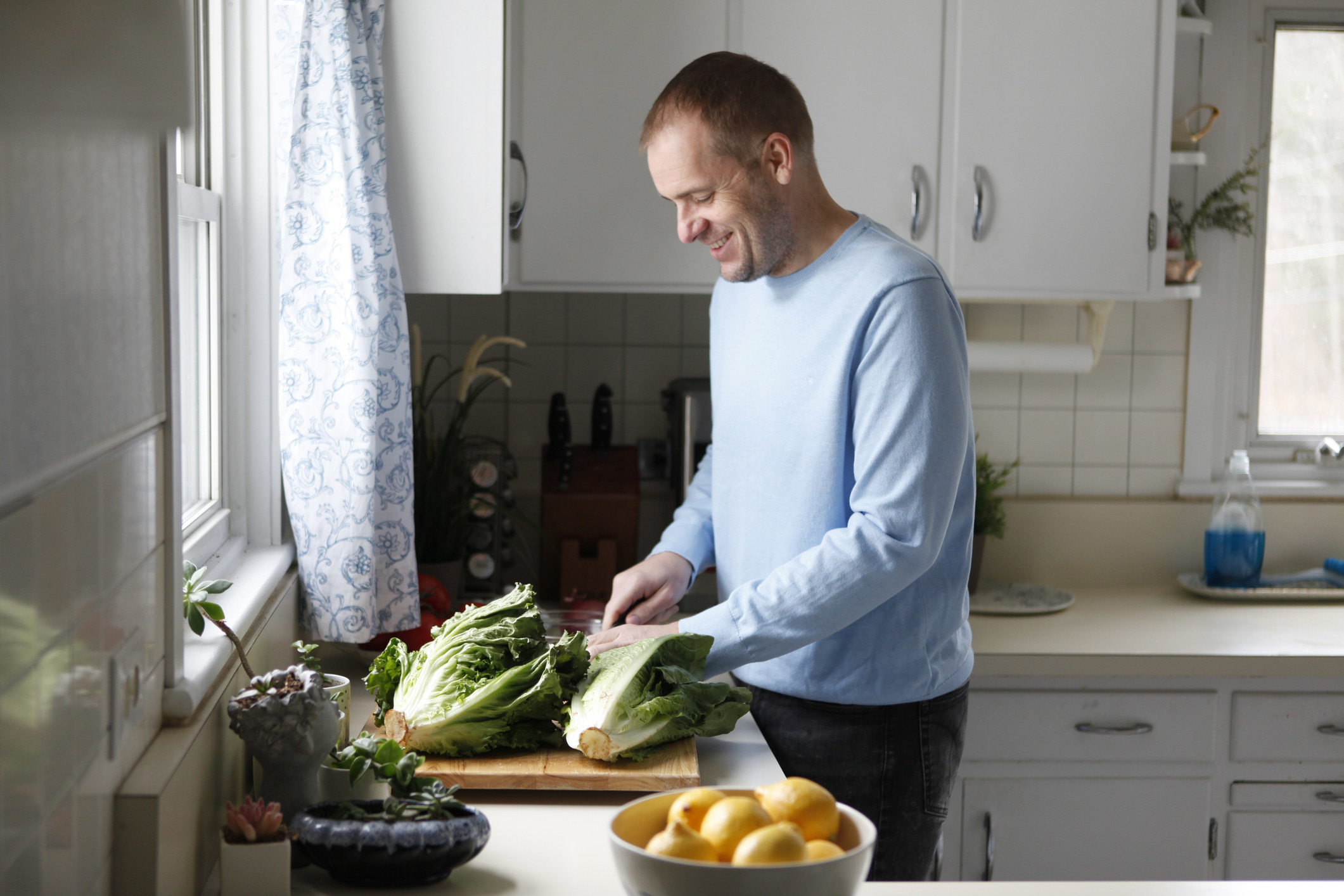 A man cutting vegetables in his kitchen