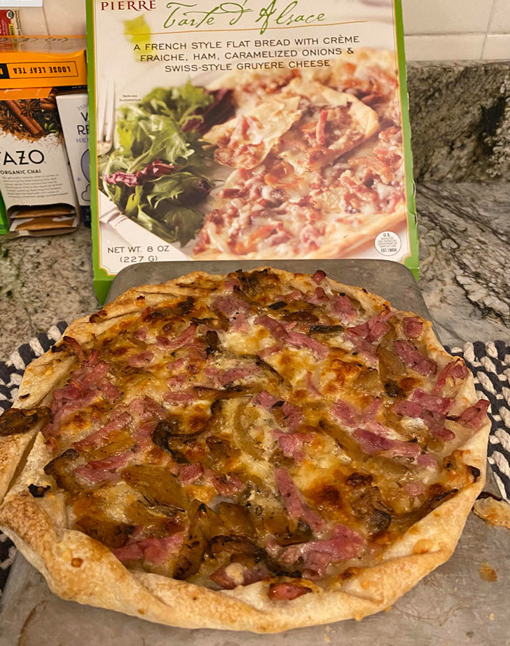 A cooked Tarte d&#x27;Alsace next to the box.