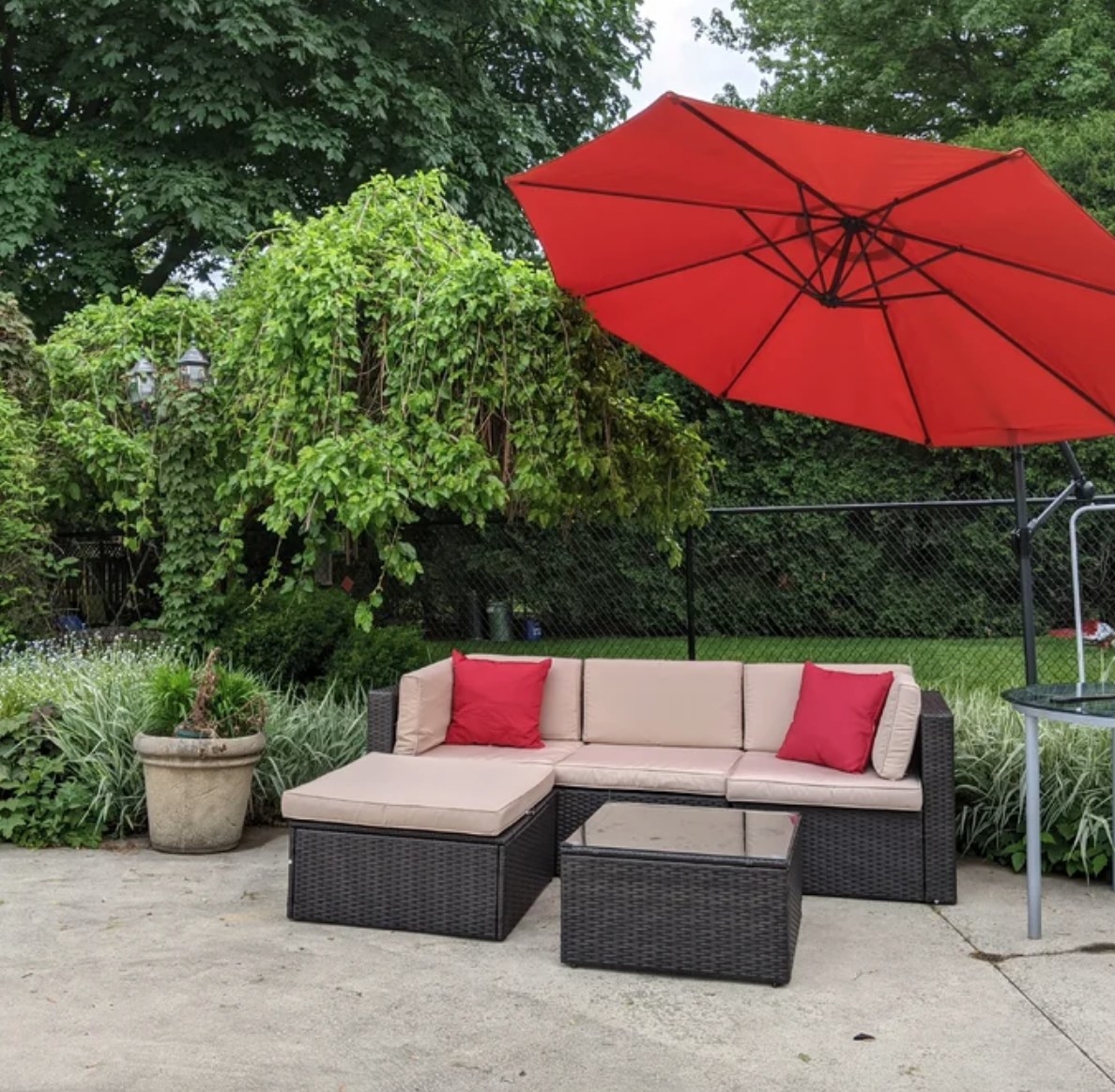 a sectional and it&#x27;s matching chaise and coffee table in a backyard under a large red umbrella
