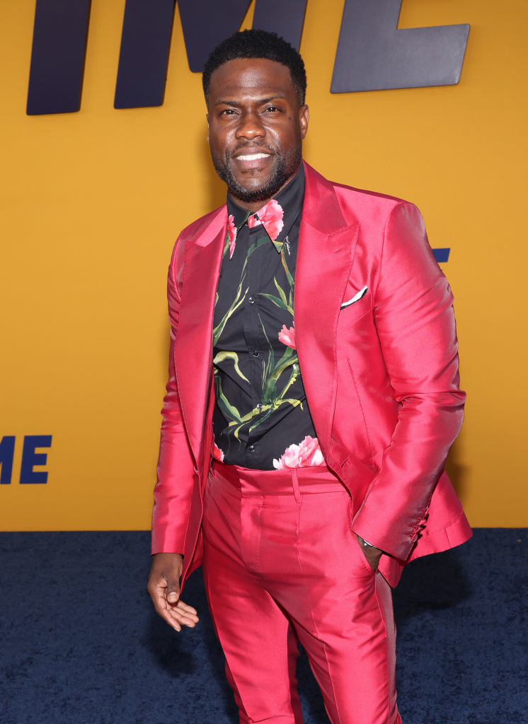 Kevin smiling on the red carpet in a shiny, bright suit