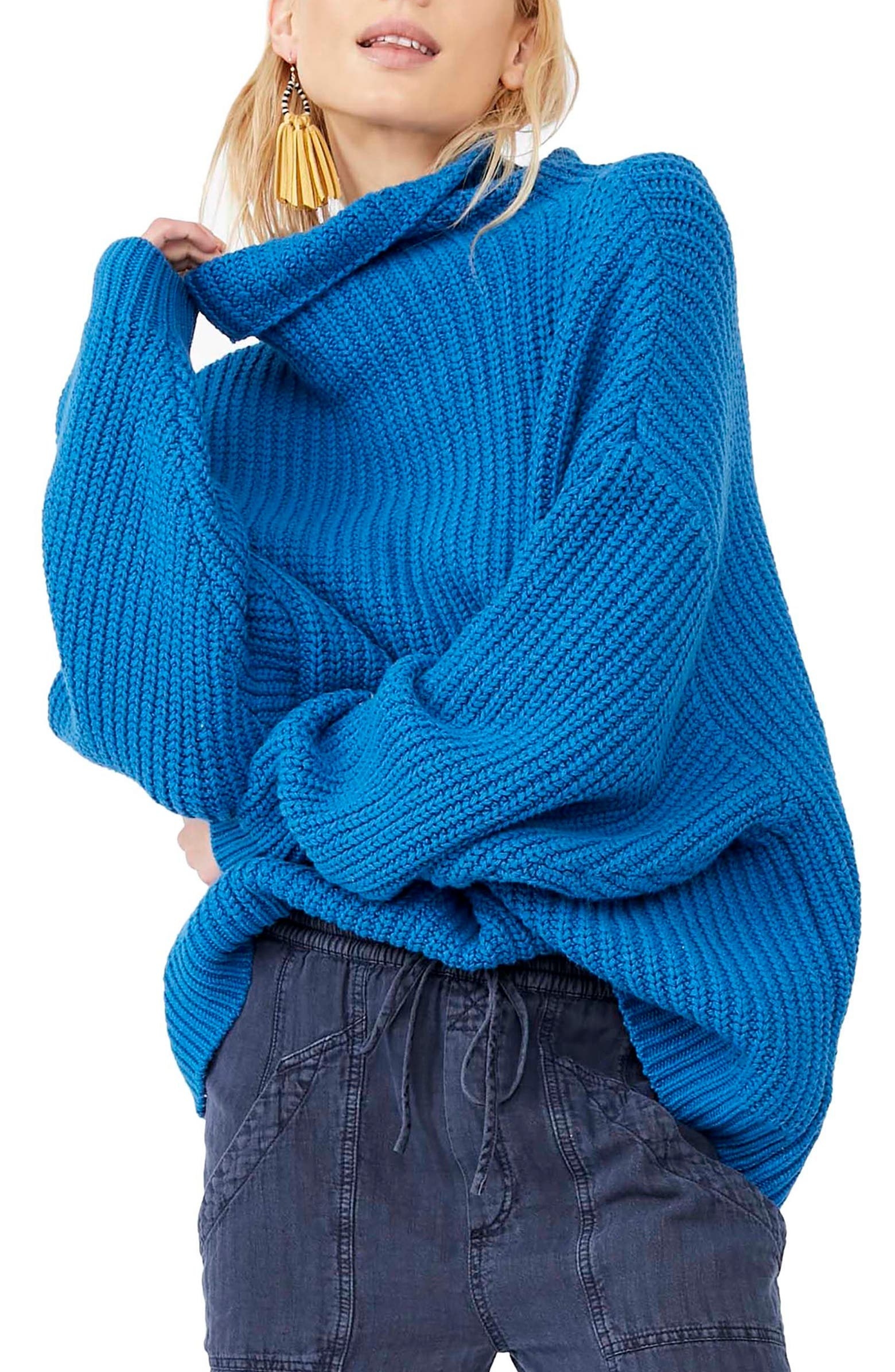 Model wearing bright blue sweater with long sleeves and rolled over turtleneck