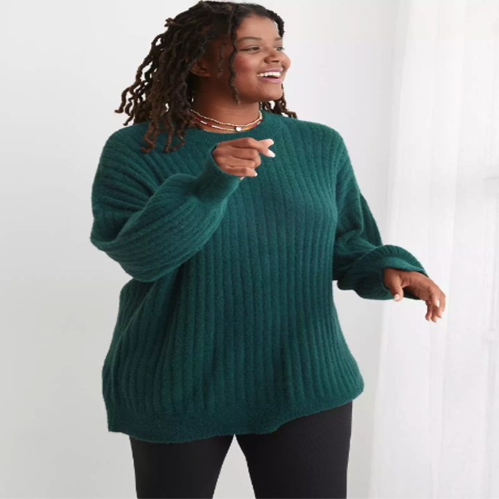 a model in a soft dark green ribbed sweater