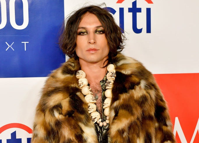 Ezra on the red carpet wearing a furry coat and skull necklace