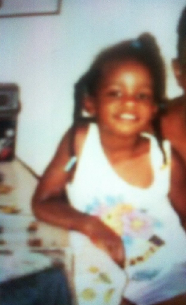 Blurry photo of a smiling young child in a sleeveless outfit