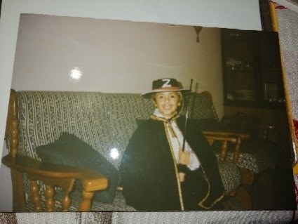 A smiling young child in the Zorro outfit, including a &quot;Z&quot; hat and cape
