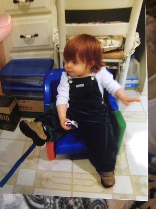 Toddler sitting in a chair and wearing overalls