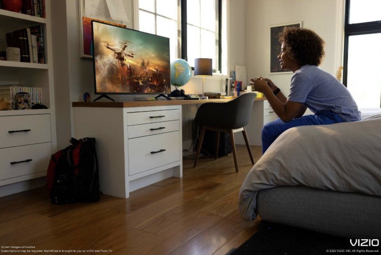 Someone sitting on bed playing a video game on the TV