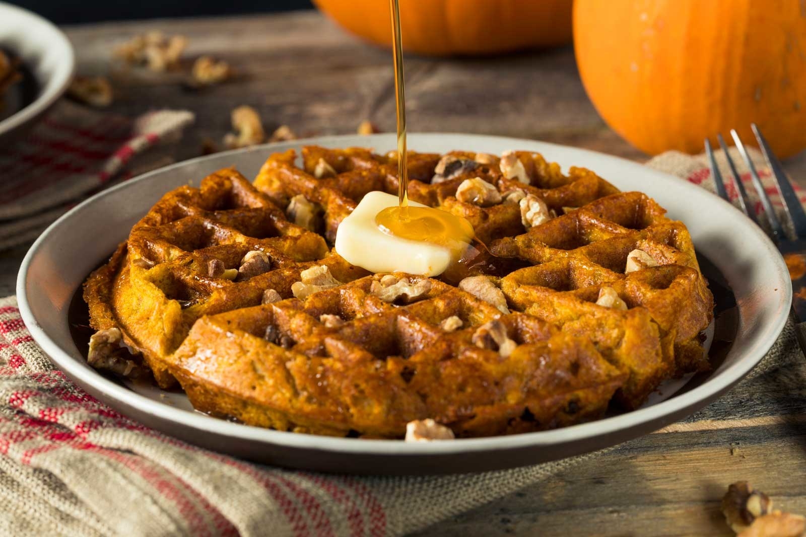 maple syrup being poured on pumpkin waffles