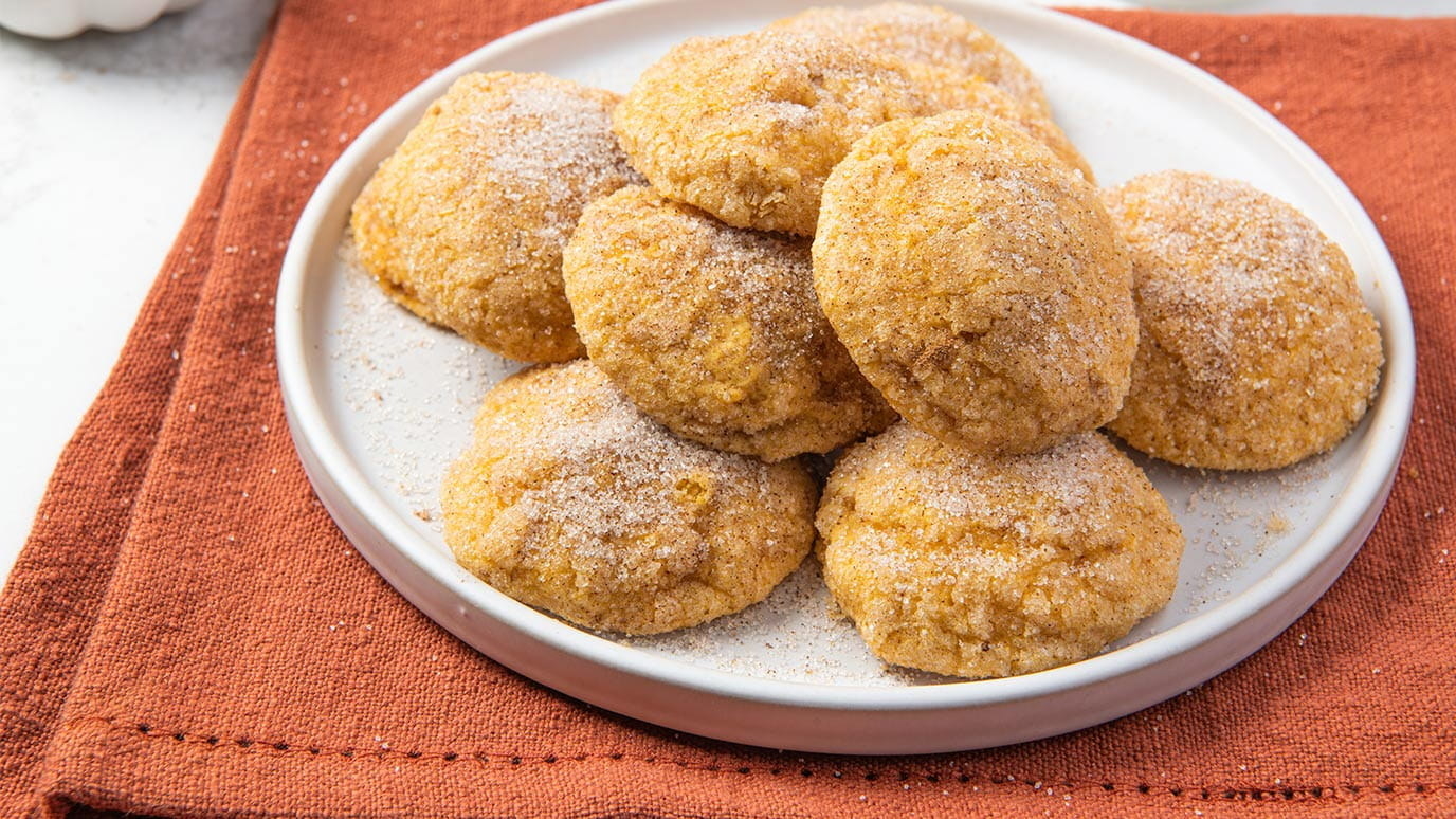 a plate of pumpkin spice snickerdoodle cookies dusted with sugar on a table