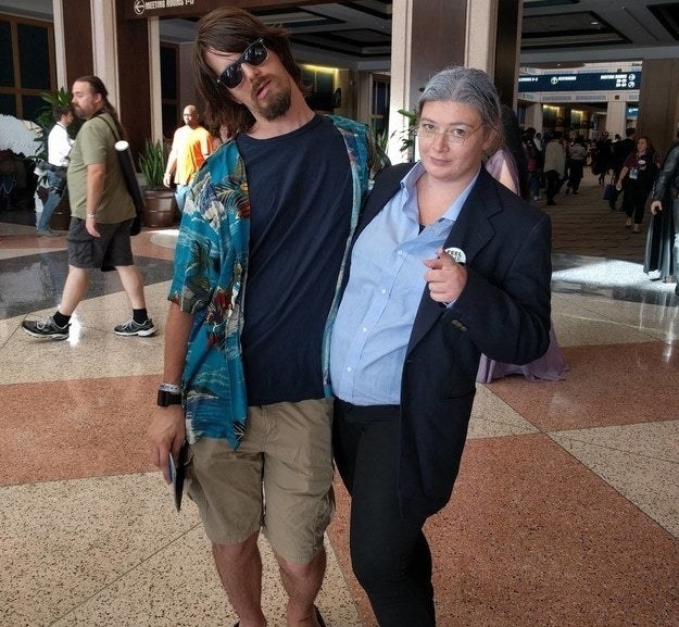 One man wearing a Hawaiian shirt and sunglasses and one woman dressed like Bernie Sanders