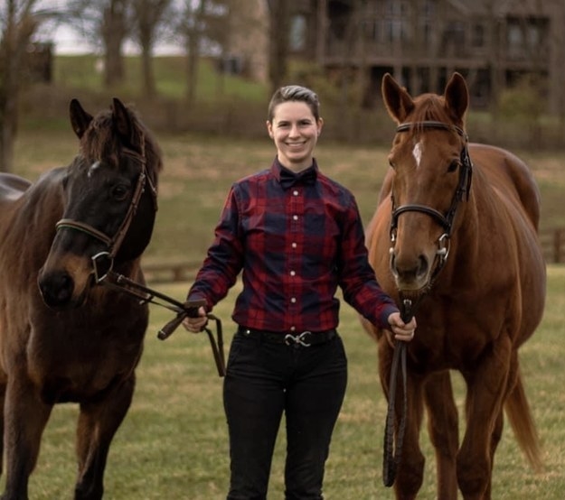 a person standing with two horses and wearing flannel shirt and pants