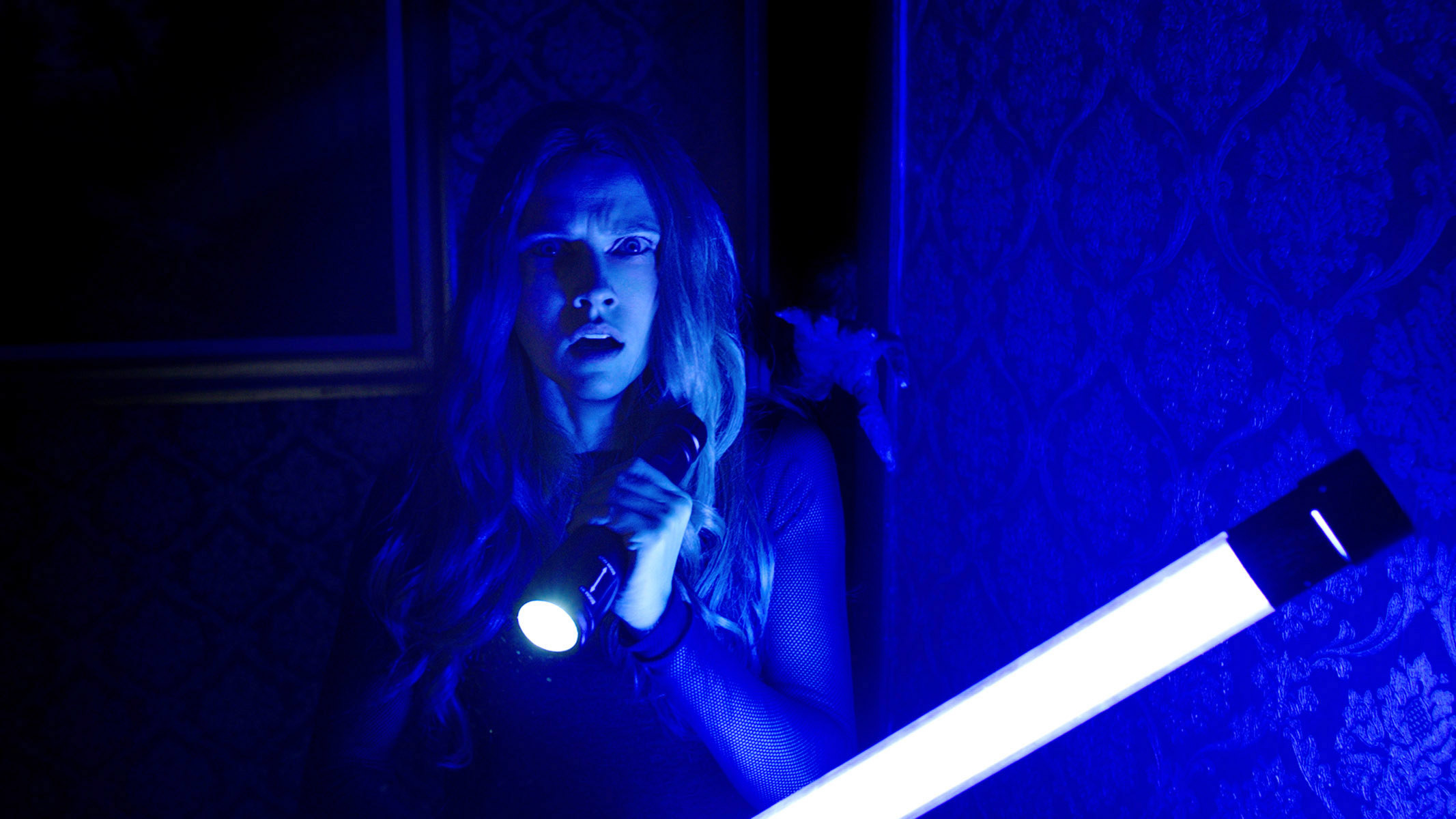 A woman holds up a blue flashlight