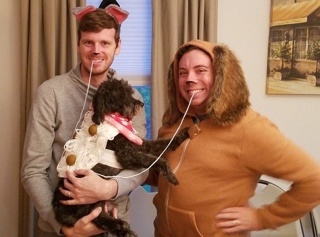 Two people dressed as dogs with a real dog dressed as spaghetti