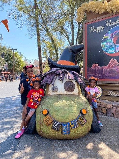 author and her daughters in front of a halloween-themed car