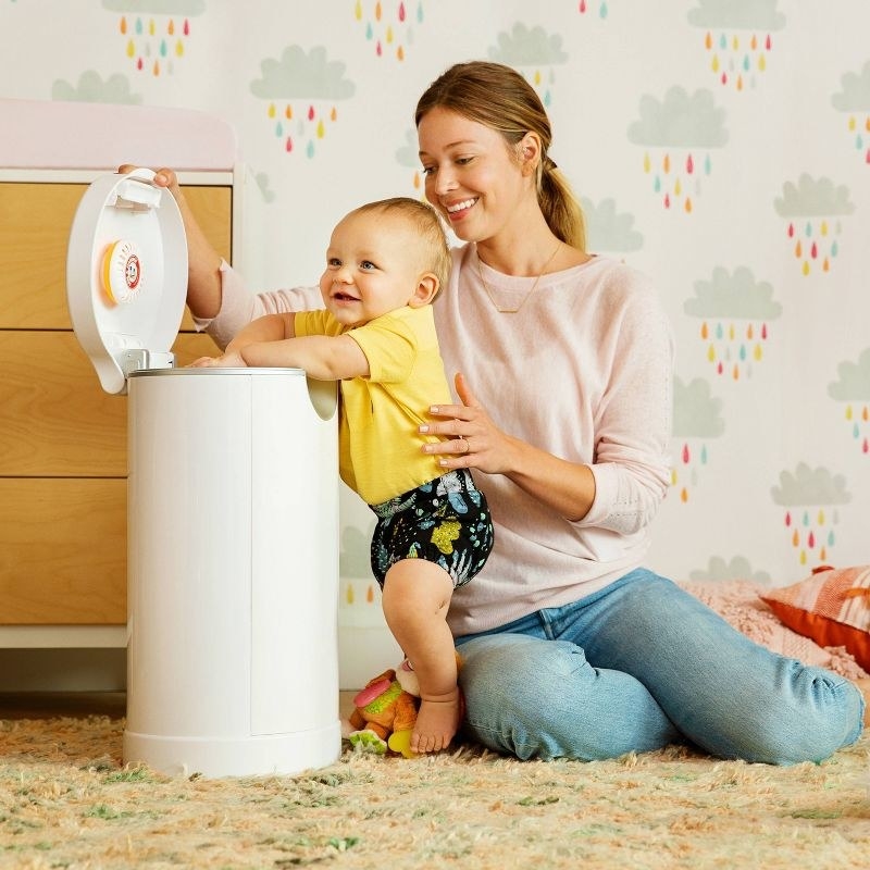parent with baby and diaper pail