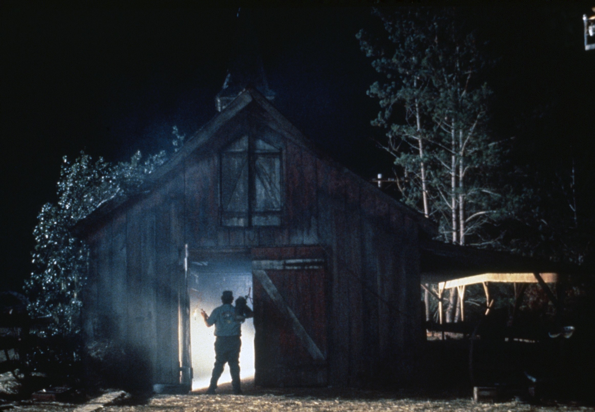 A man stands in front of a brightly lit cabin