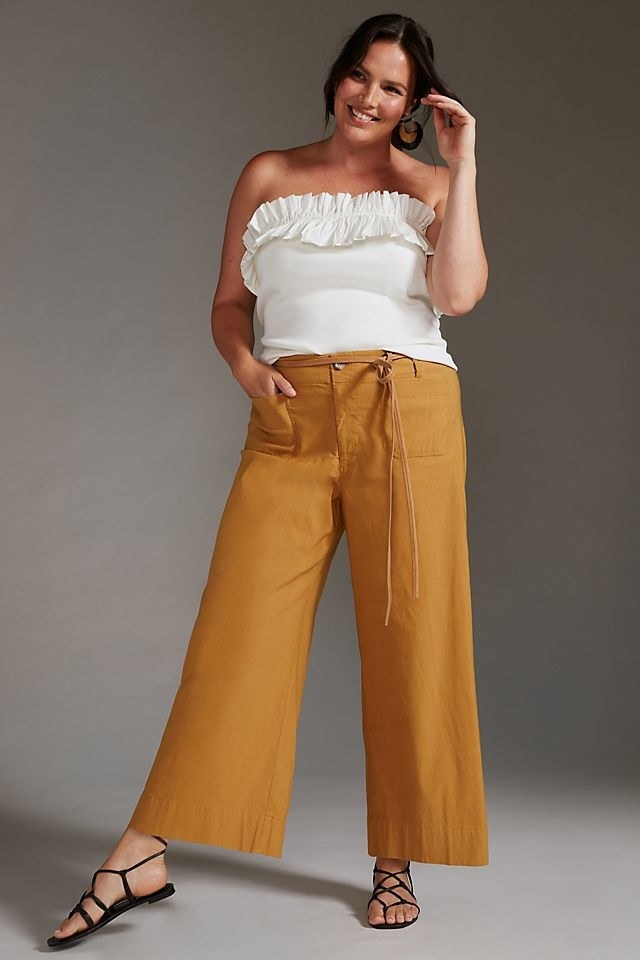 model wearing mustard-colored cropped pants and a white top
