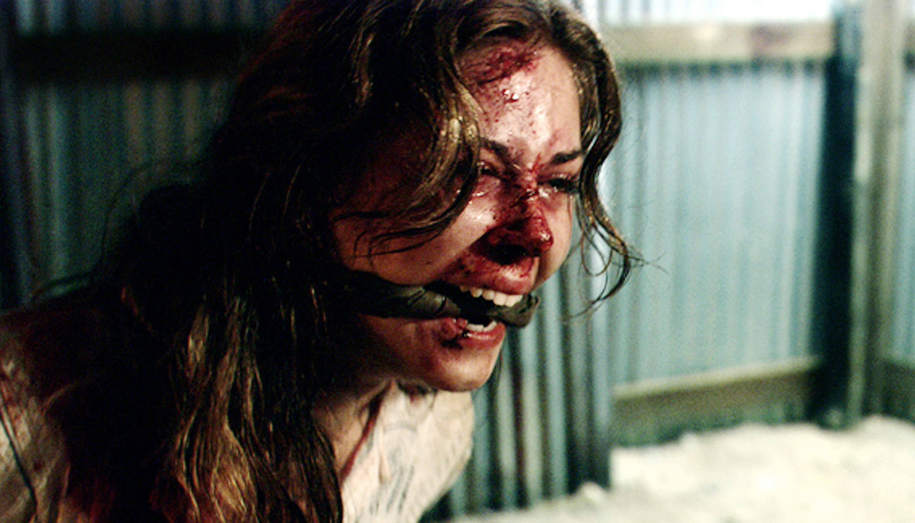 A bloodied woman with a gag in her mouth
