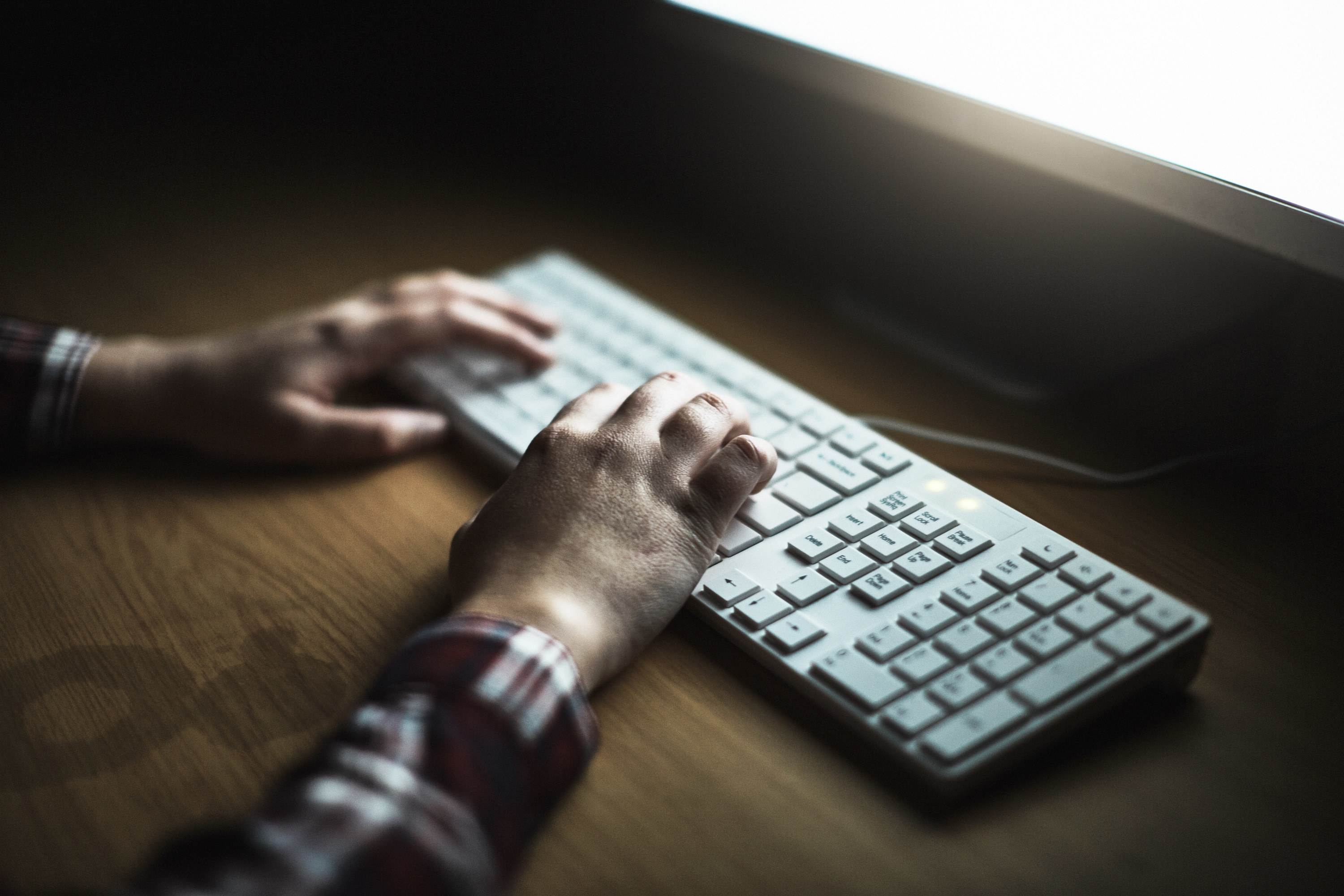 person typing on a keyboard in the dark.