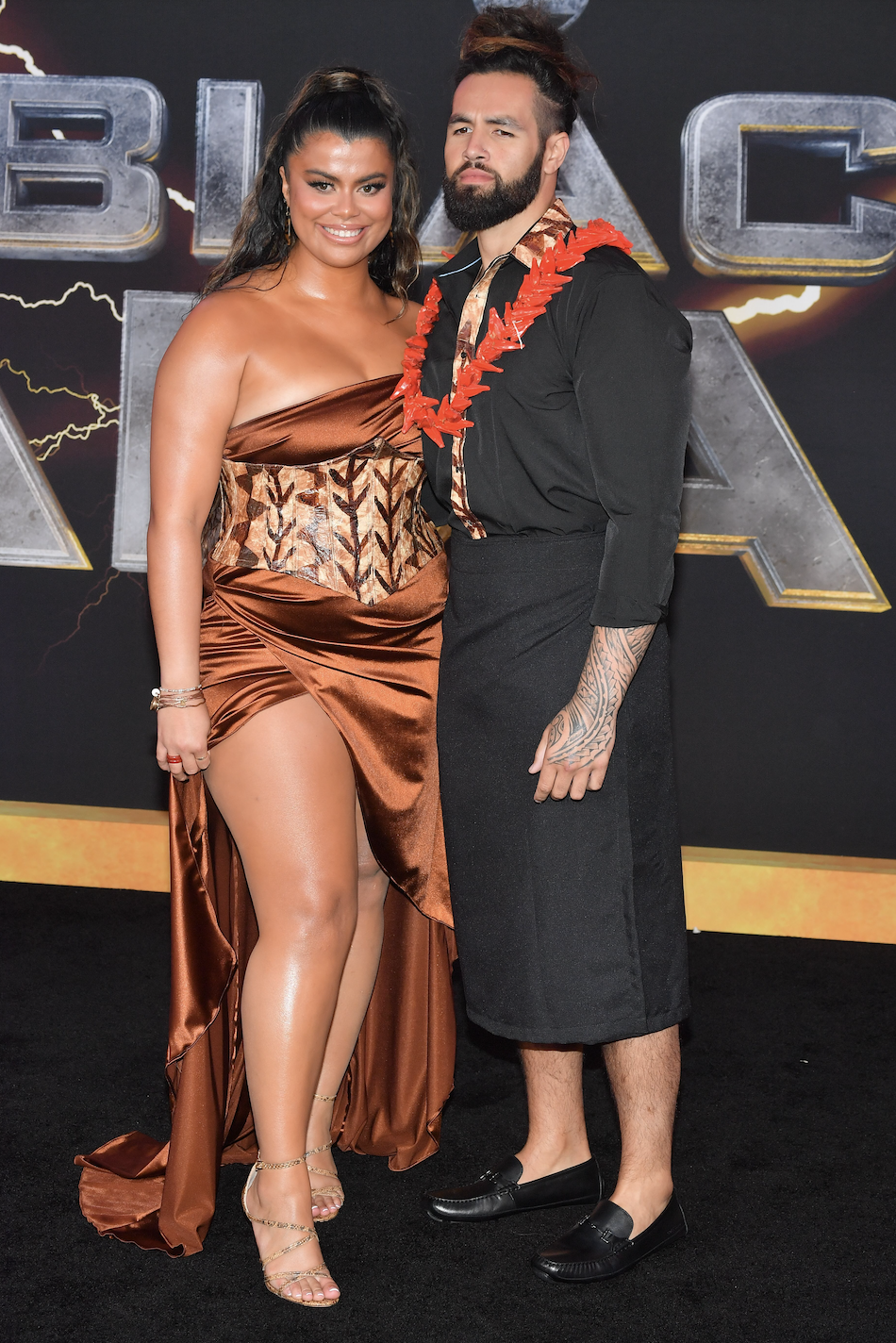 Drew poses with another person on the red carpet while wearing strapless satin gown with a tapa corset