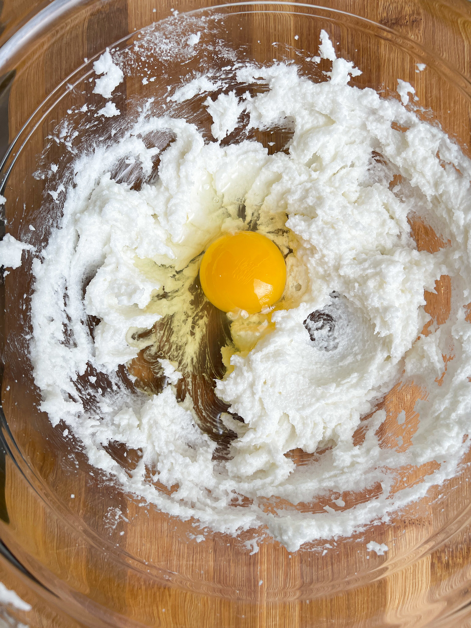 egg in the middle of whipped sugar and shortening in a large glass bowl