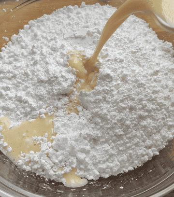 adding wet ingredients to powdered sugar in bowl