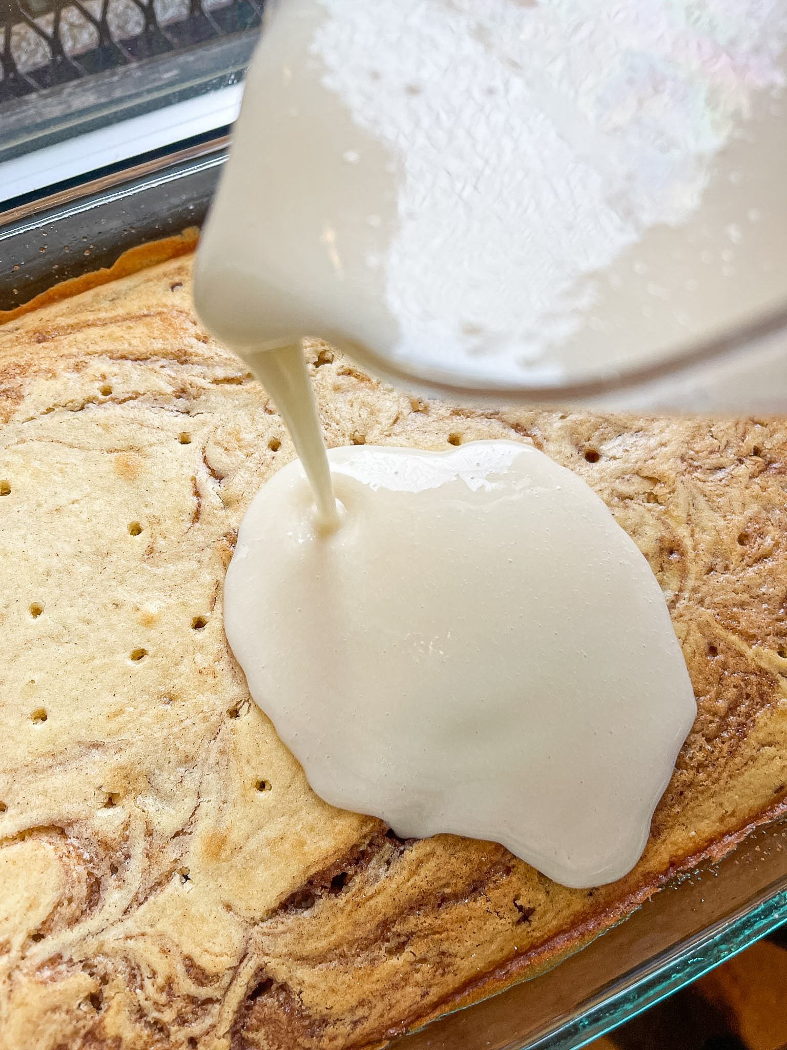 pouring the icing all over the top of the cake