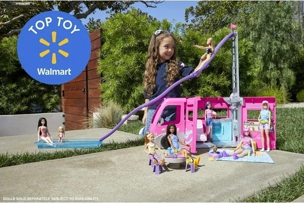 Little girl playing outside with Barbie camper