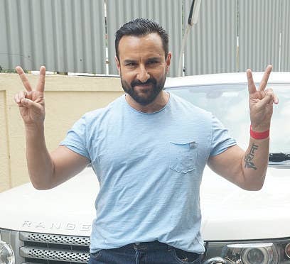 Saif Ali Khan leaning against a car and holding up two &quot;peace&quot; signs with his hands