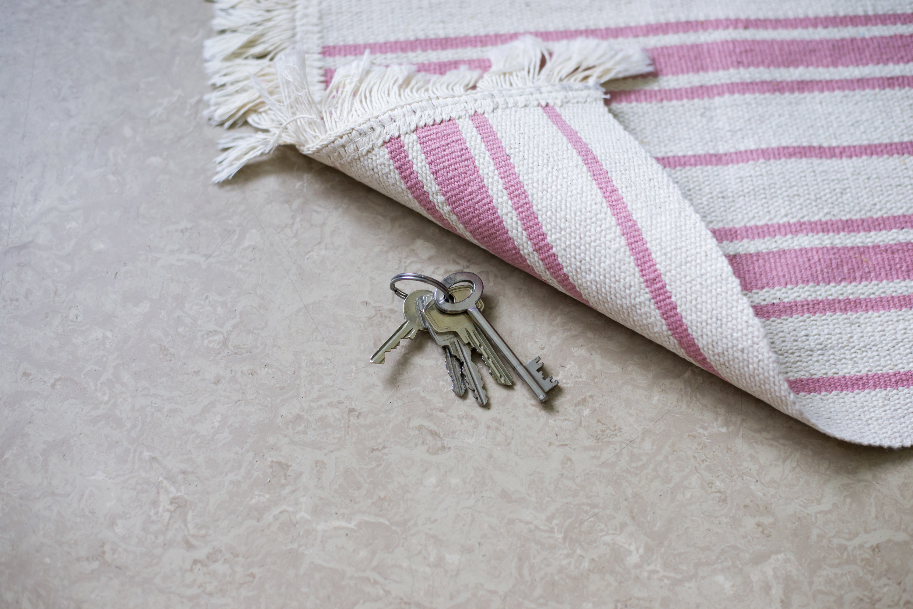 keys on the floor with a flipped over corner of a rug just above them