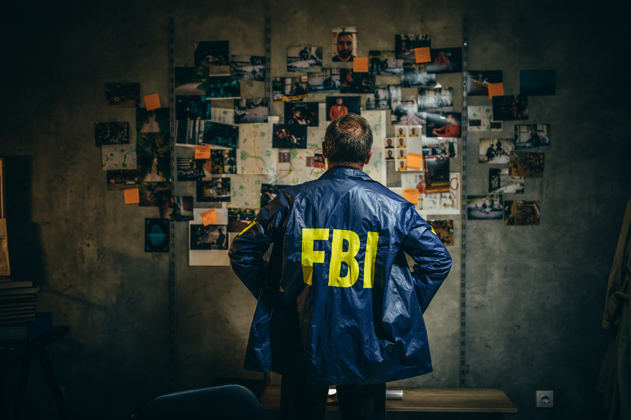 FBI agent looking at a wall full of photos