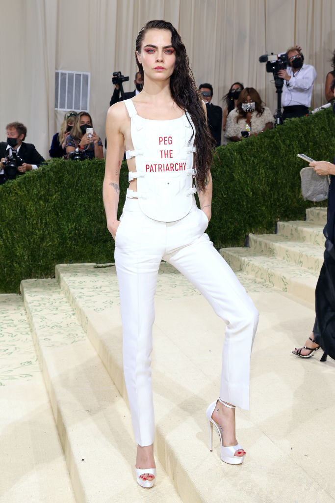 Cara Delevingne standing on steps and wearing a &quot;peg the patriarchy&quot; top