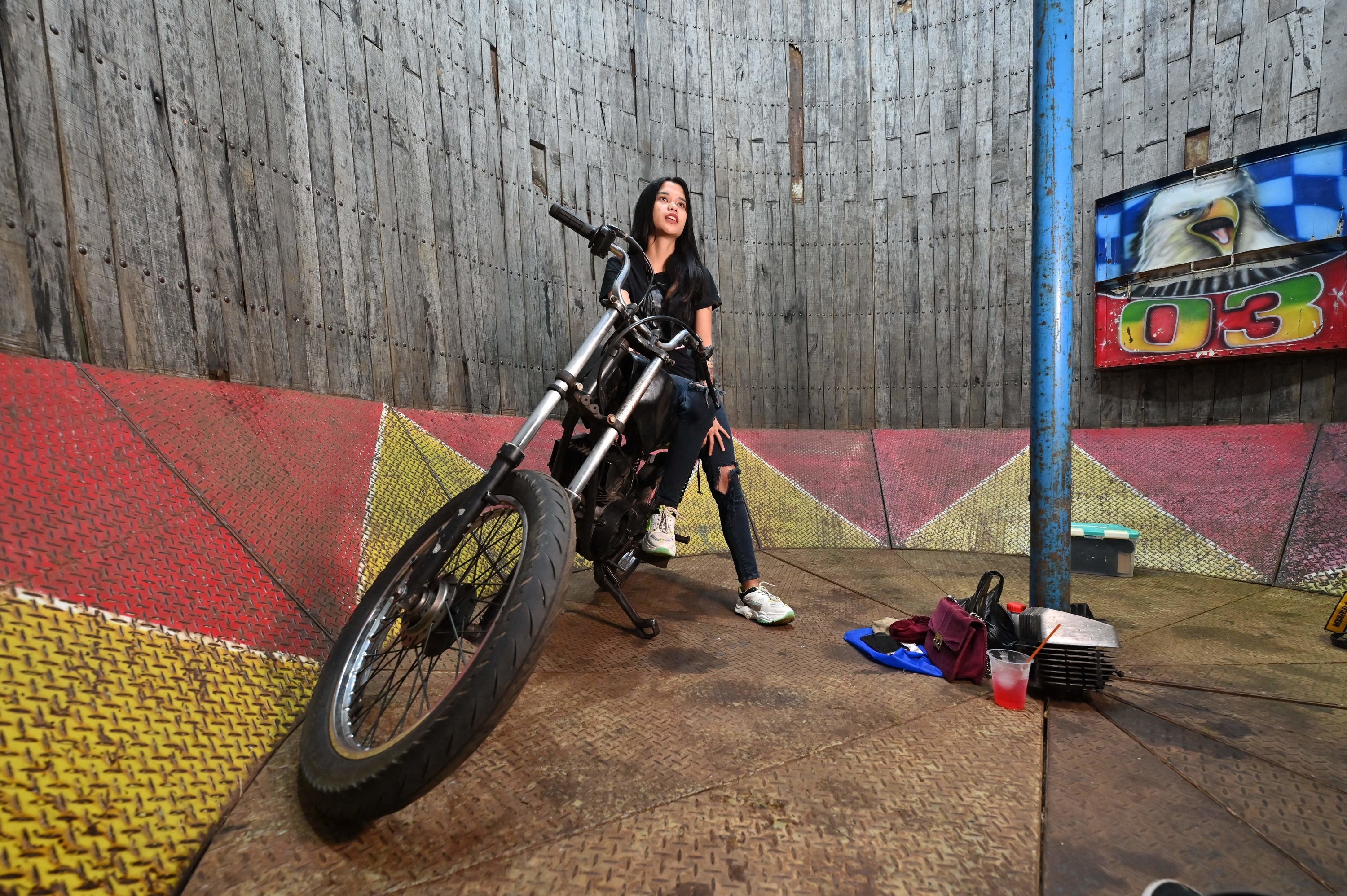 Karmila Purba, a 23 year old daredevil, sitting on a motorcycle resting at the bottom of a &quot;Well of Death.&quot; 