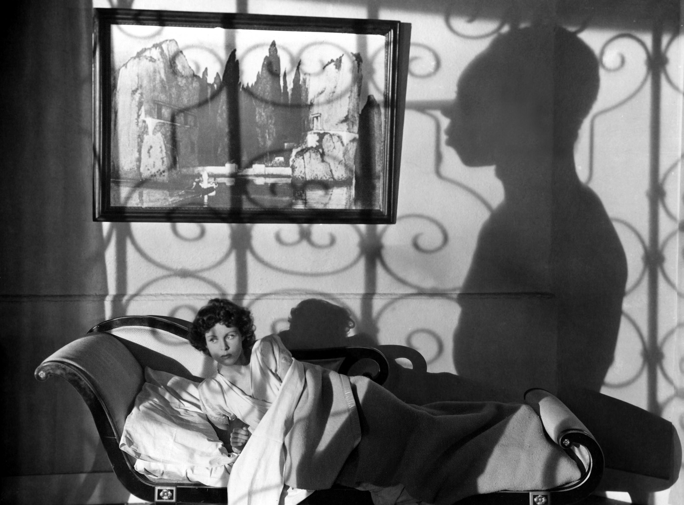 A woman looks out the window as a shadow comes into view
