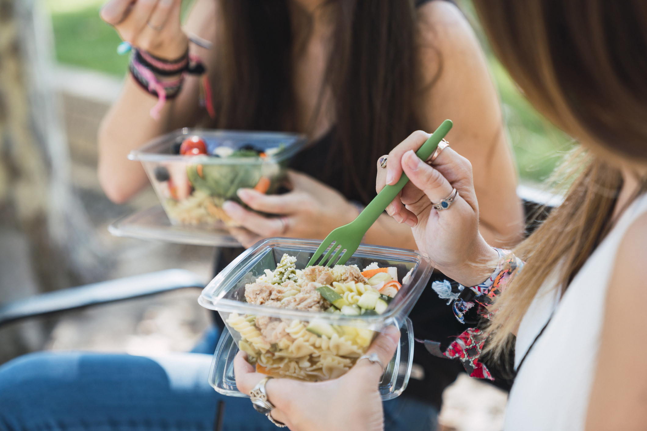 people eating salads from a plastic container