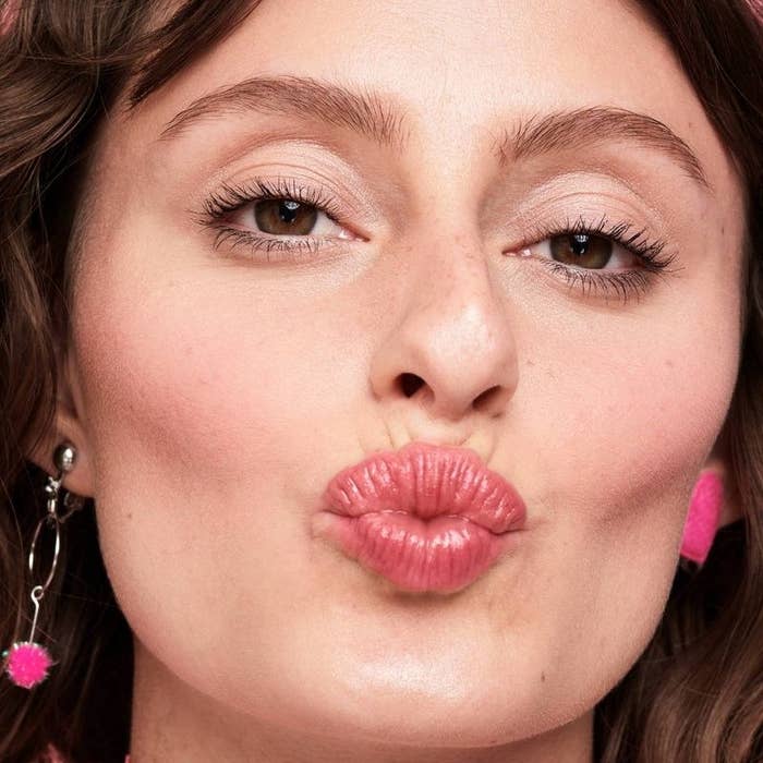 A person wearing pink lipstick with fluffy lashes