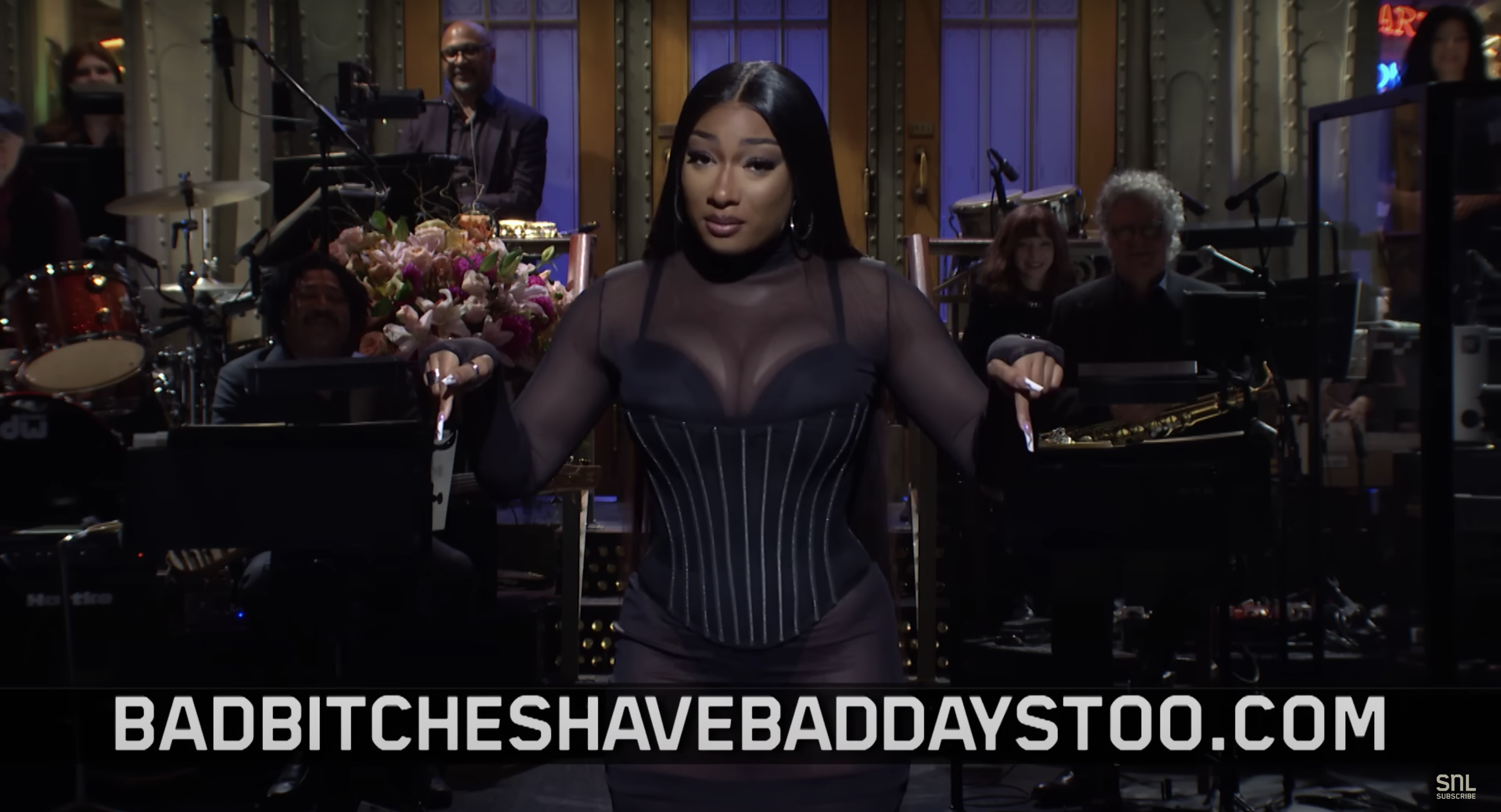 Megan on the SNL stage with "badbitcheshavebaddaystoo.com" text below the image