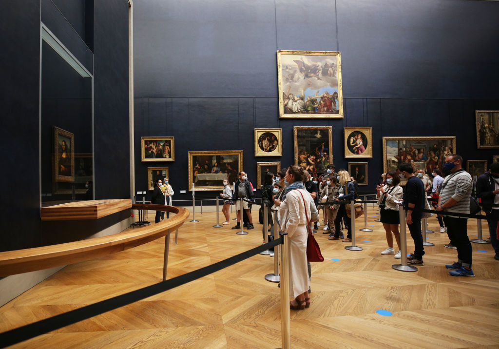 Visitors wearing face masks look at the painting Mona Lisa at the Louvre Museum