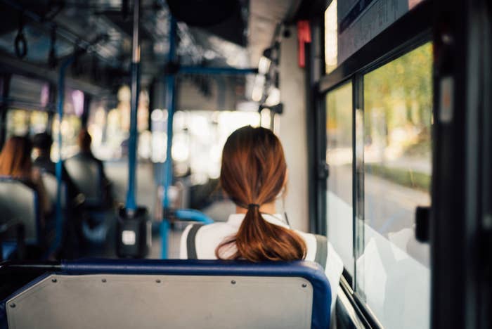 A rear view of a woman sitting on a bus