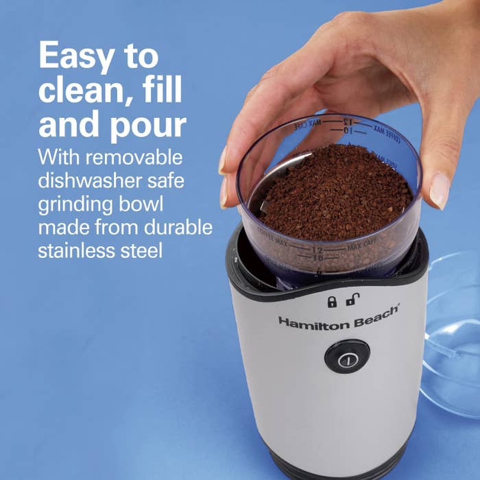 Someone holding open the grinder with beans finely roasted. Text reads "easy to clean, fill and pour with removable dishwasher safe grinding bowl made from durable stainless steel"