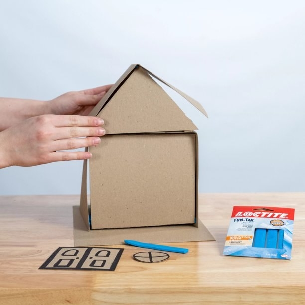Model using putty to construct a cardboard house