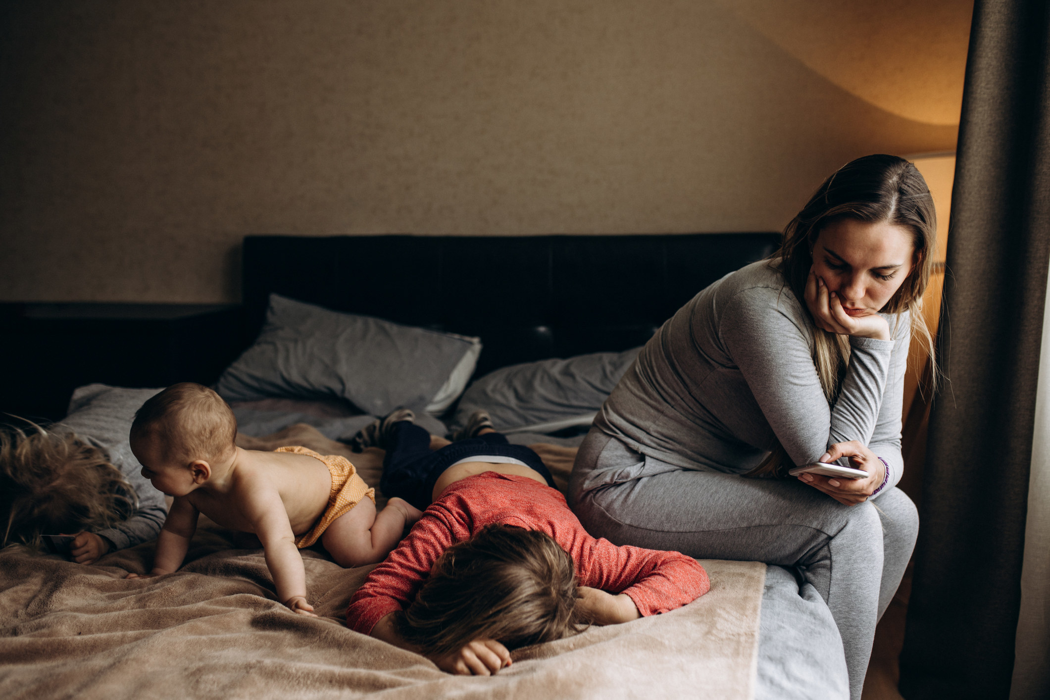 A woman on a bed looking at her children